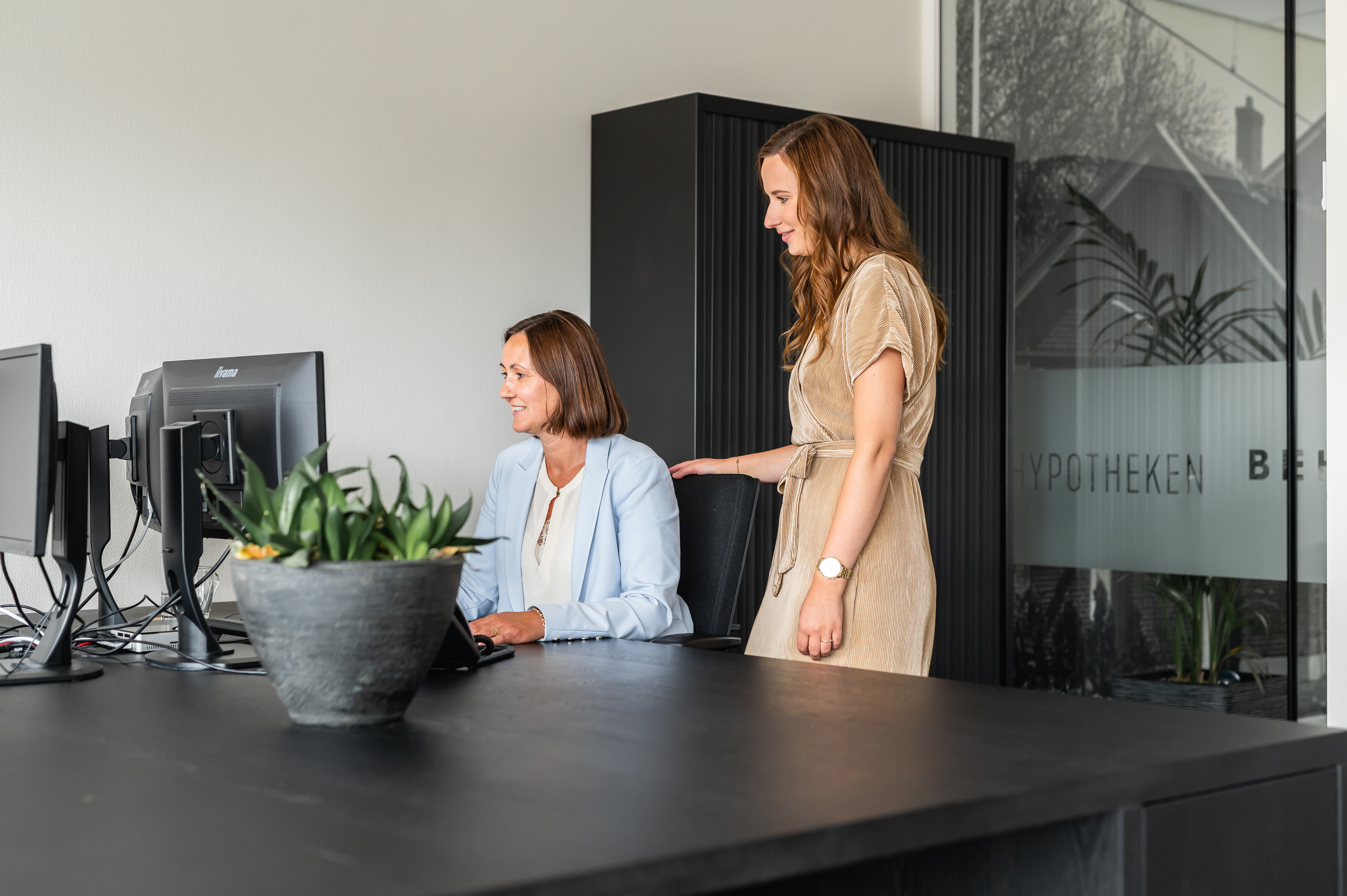 De twee collega’s kijken samen naar de computer.